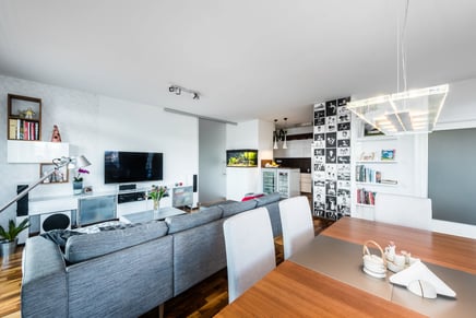 Moderní obývací pokoj s jídelnou, šedá sedačka, TV stěna a akvárium.